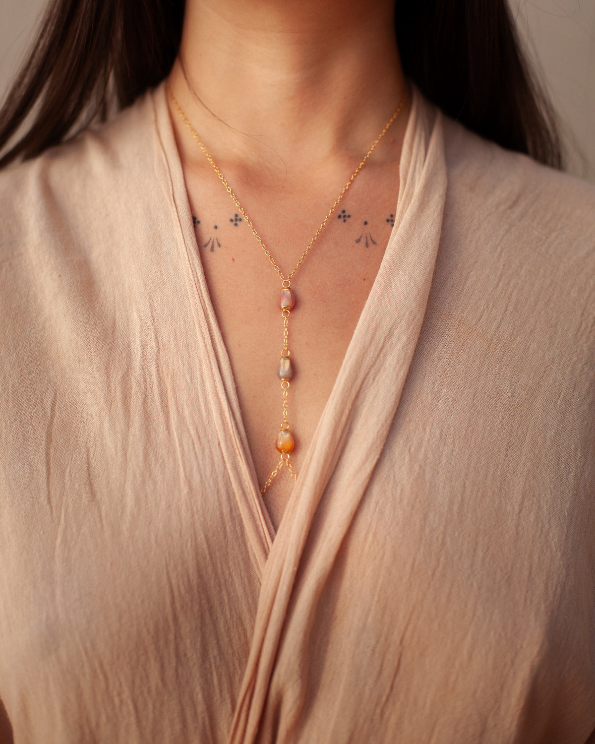 Gold lariat necklace with Glass Gem corn gems, worn with a blush wrap top
